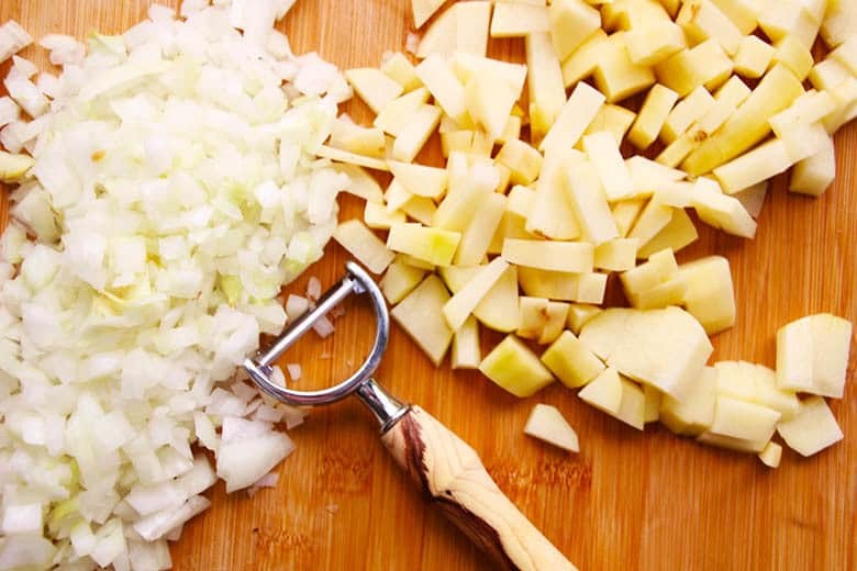 Diced onions and potatoes on a cutting board.