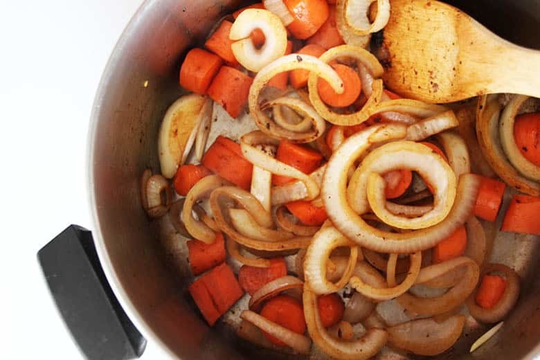 A pan of carrots and onions with the brown bits from the fond.