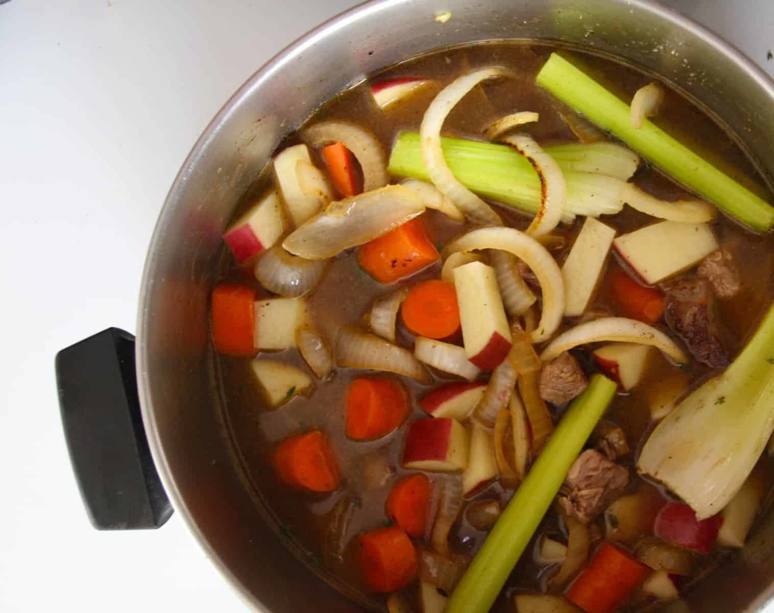 A pot of soup ingredients simmering on the stove.