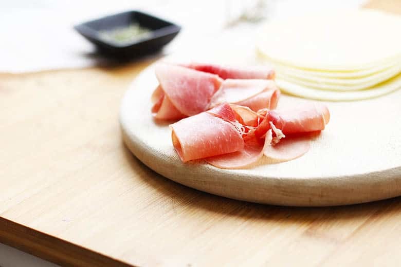 Prosciutto and provolone on a cutting board.