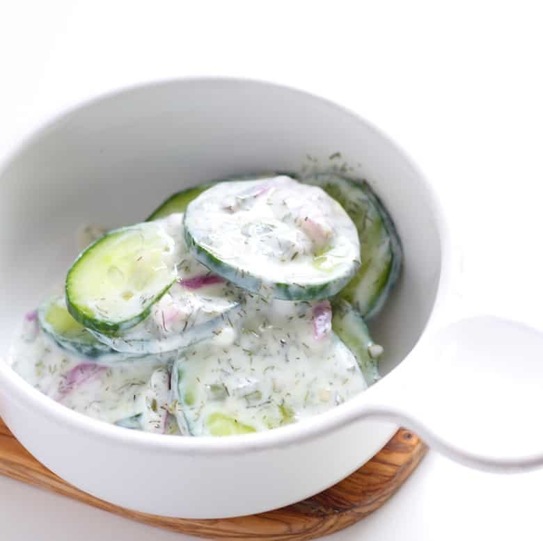 A bowl of cucumber salad in a white bowl.
