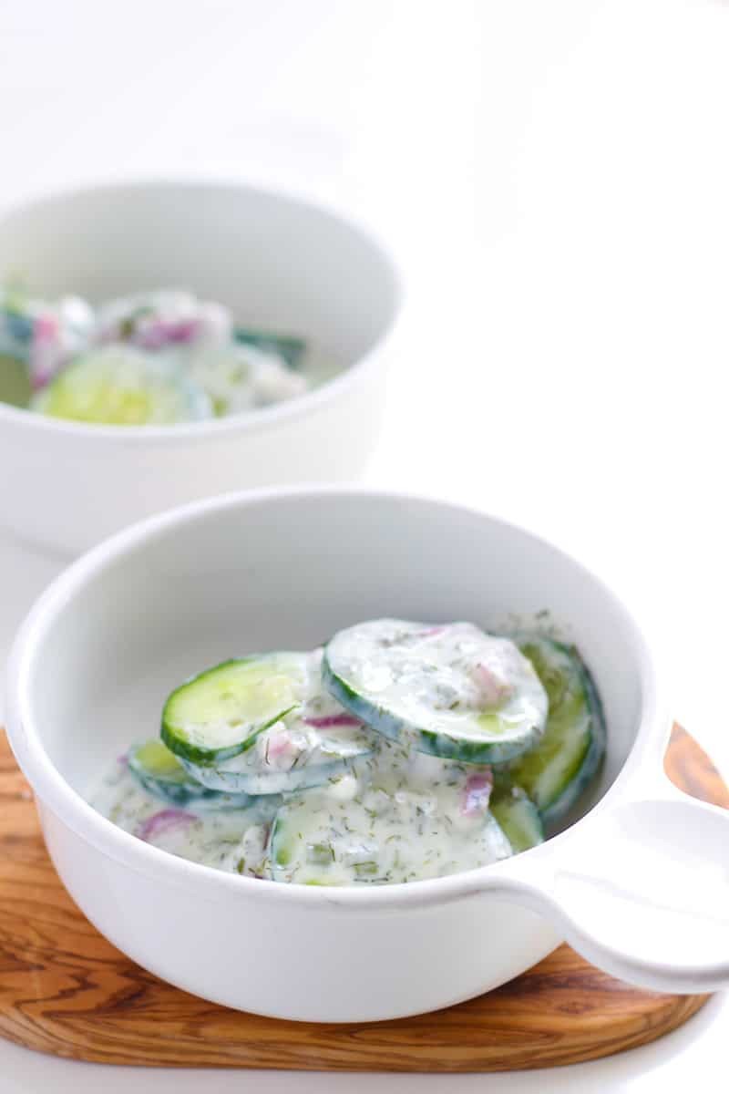 A bowl of cucumber salad in a white bowl.