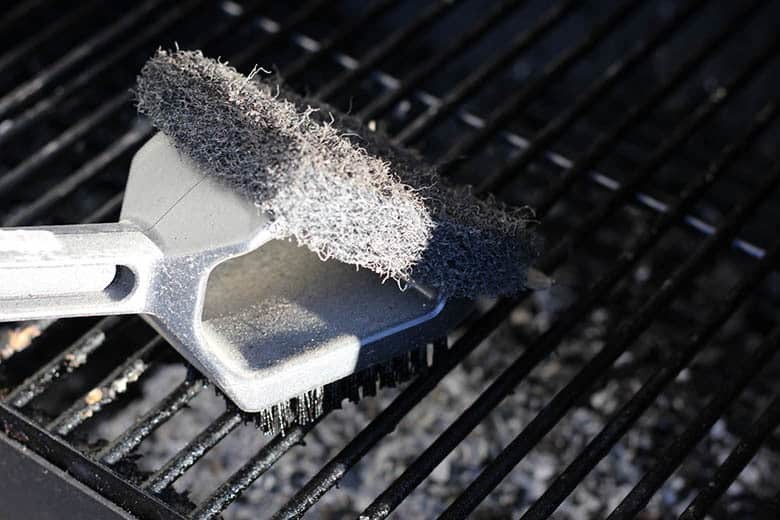 Cleaning the hot grill with a wire brush.