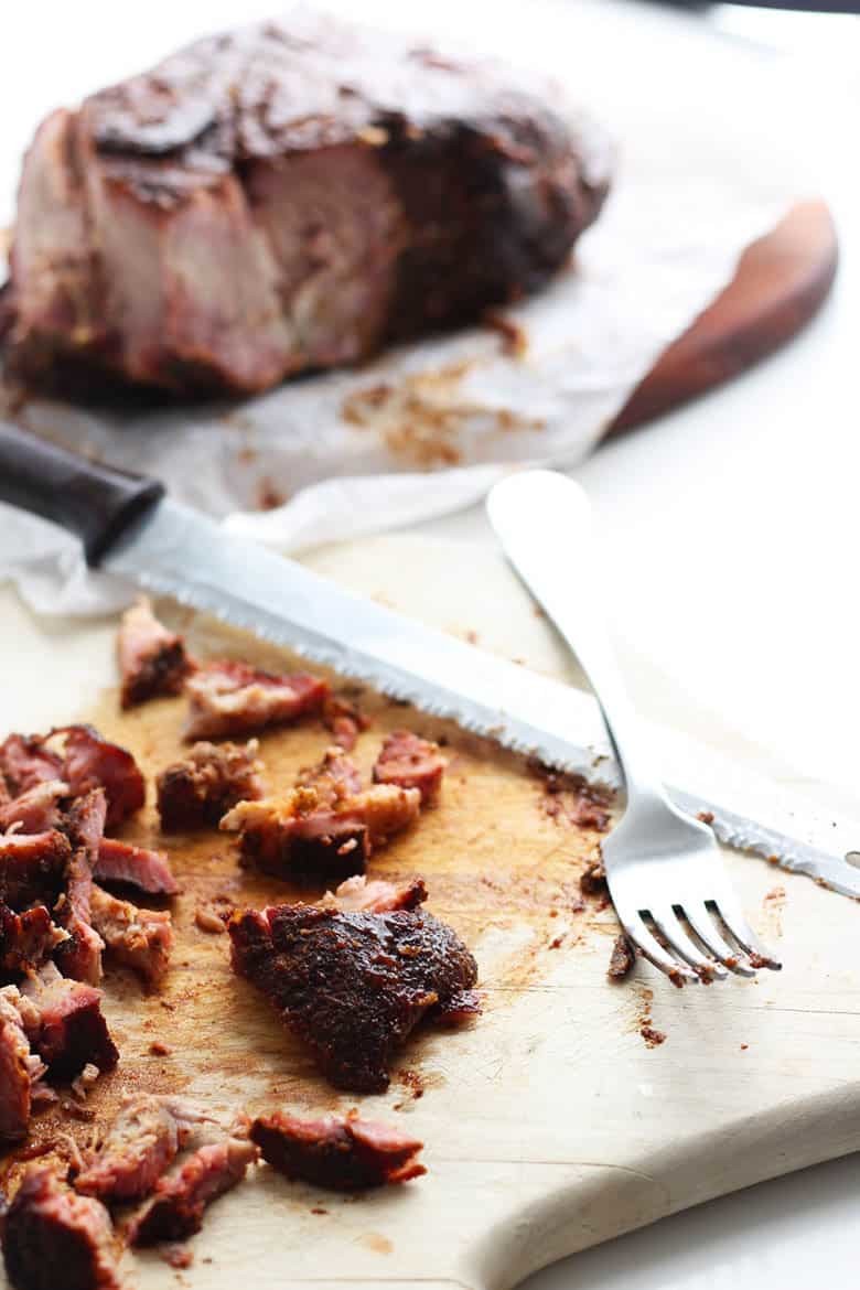 BBQ pork shredded with a fork on a cutting board.