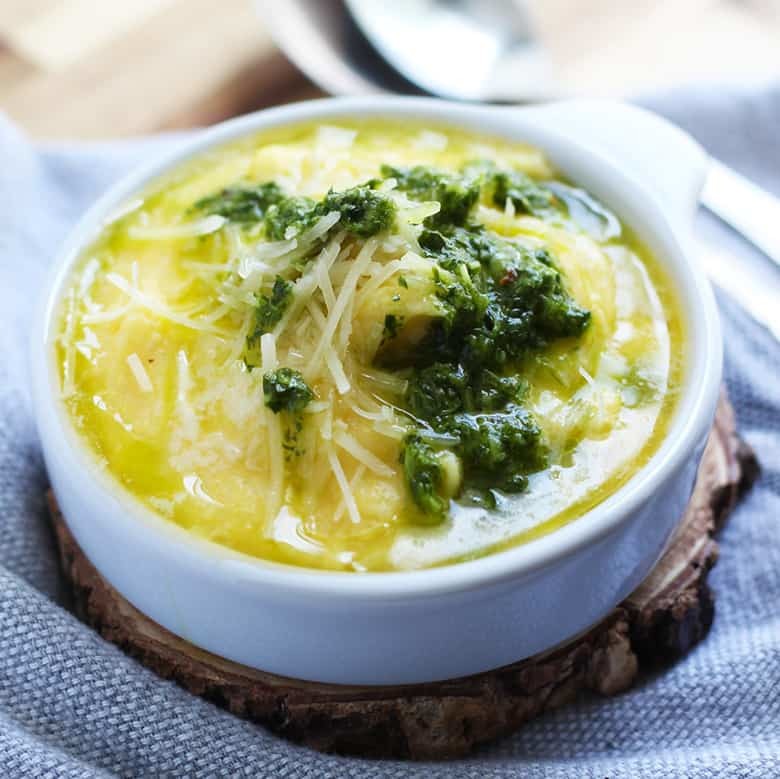 A bowl of polenta with parmesan and pesto on top.