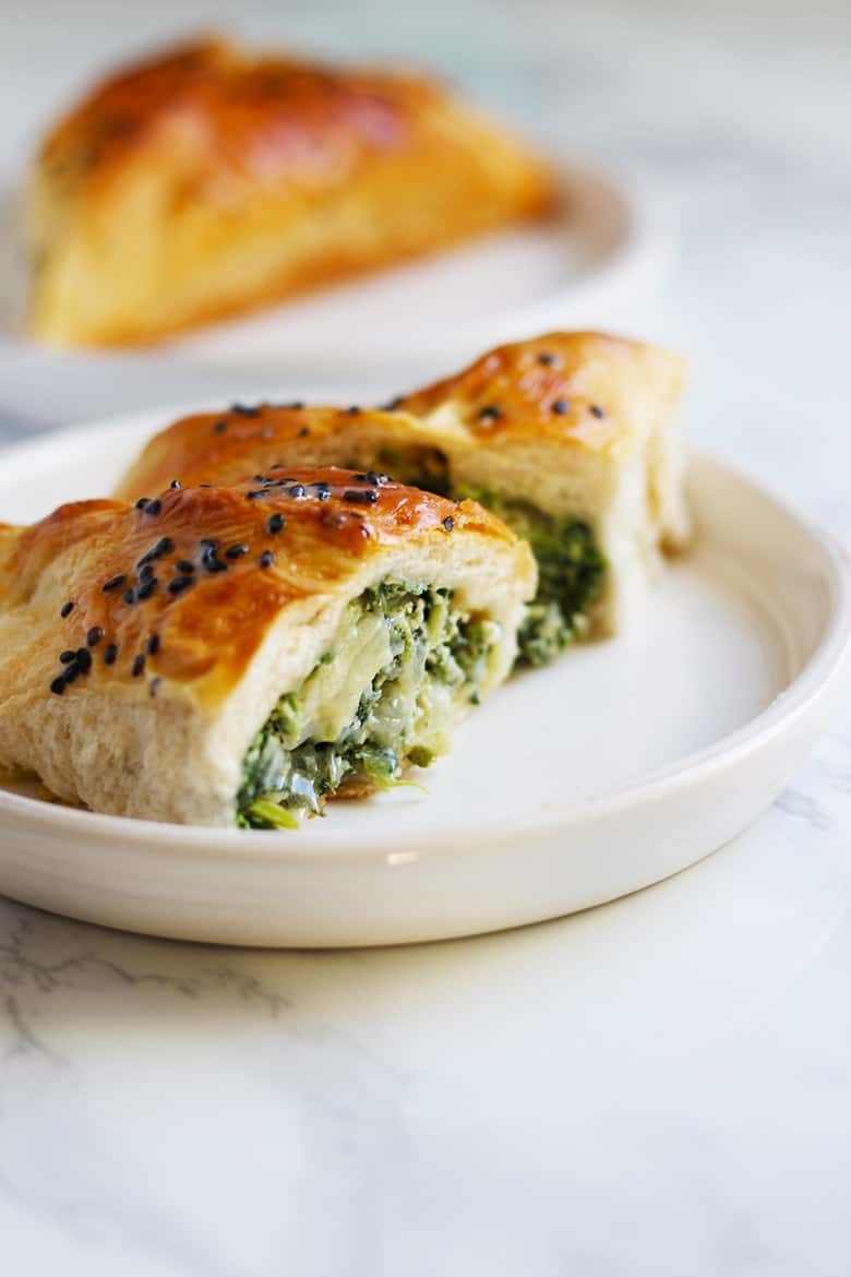 Spinach turnover cut in half on a white plate.