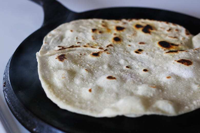 A tortilla cooking on a griddle.