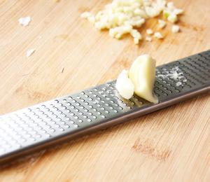 Garlic being minced on a microplaner.