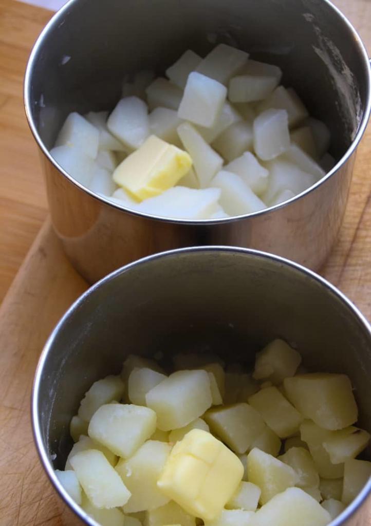 Boiled potatoes in a pot next to a pot of boiled neeps.