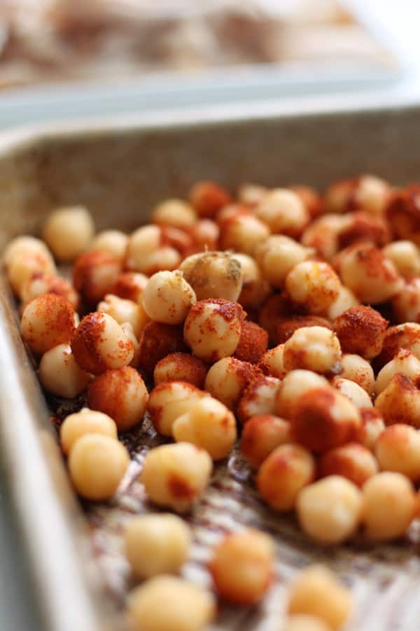 Canned chickpeas, tossed with spices on a baking sheet.