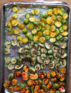 A sheet pan lined with foil filled with Brussels sprouts halves.