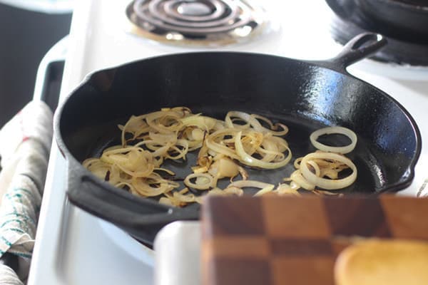 Thinly sliced onions frying in a pan.