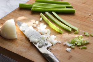 Chopped celery and onion on cutting board.