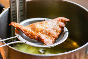 Fried wonton wrapper taken out of oil with fine mesh sieve.