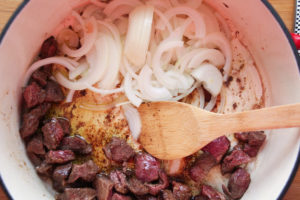 Meat and onions cooking in pot.